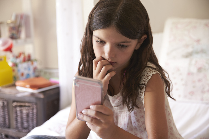 Young girl looking worried at her phone.