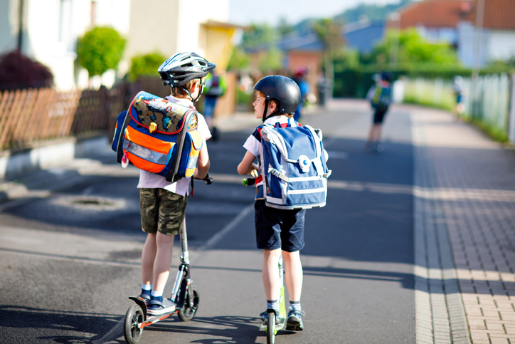 Two school boys riding scooters